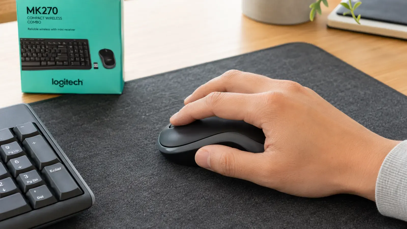 Logitech MK270 wireless mouse being used with right hand on a desk mat next to a keyboard